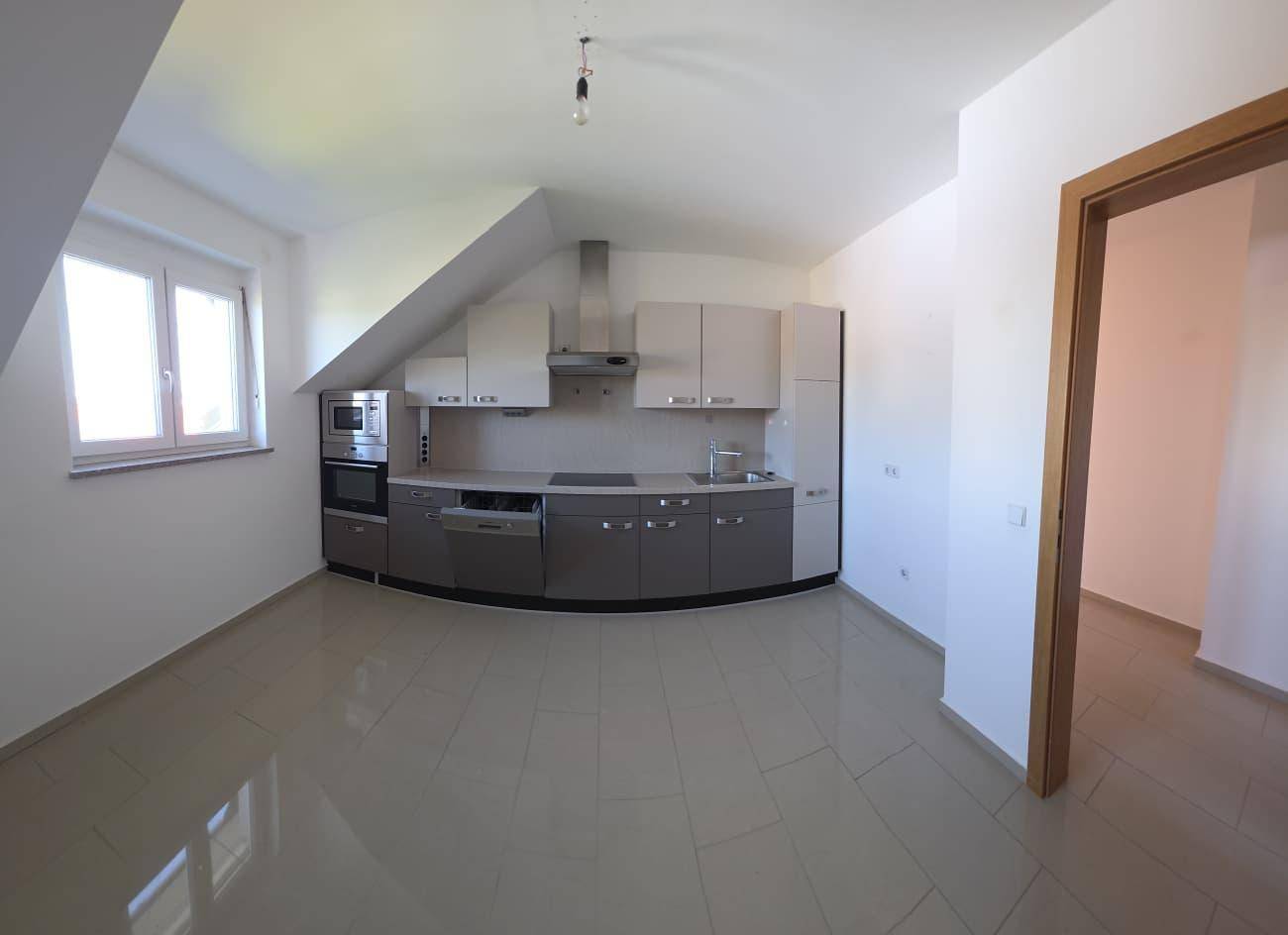 Moderne Einbauküche mit Geräten, Fliesenboden und Fenster unter der Dachschräge.