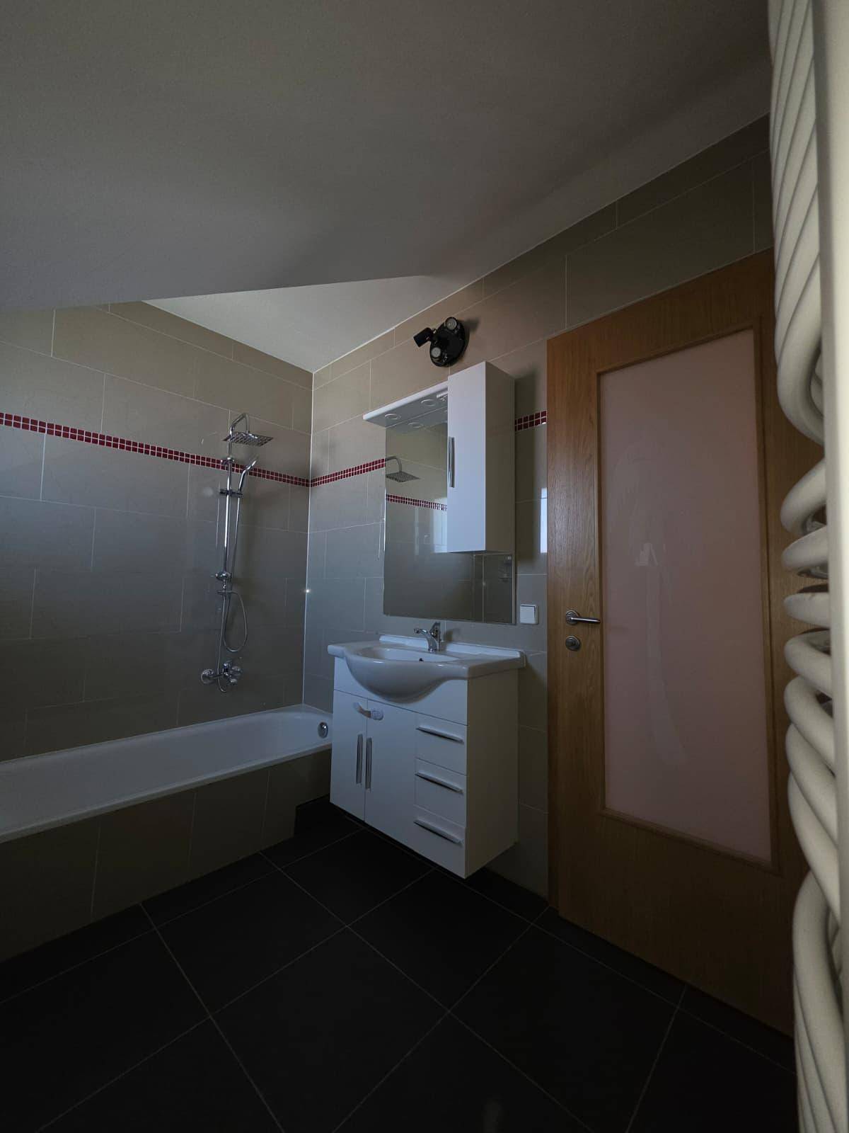 Modernes Badezimmer mit Badewanne, Waschtisch und beheiztem Handtuchhalter.