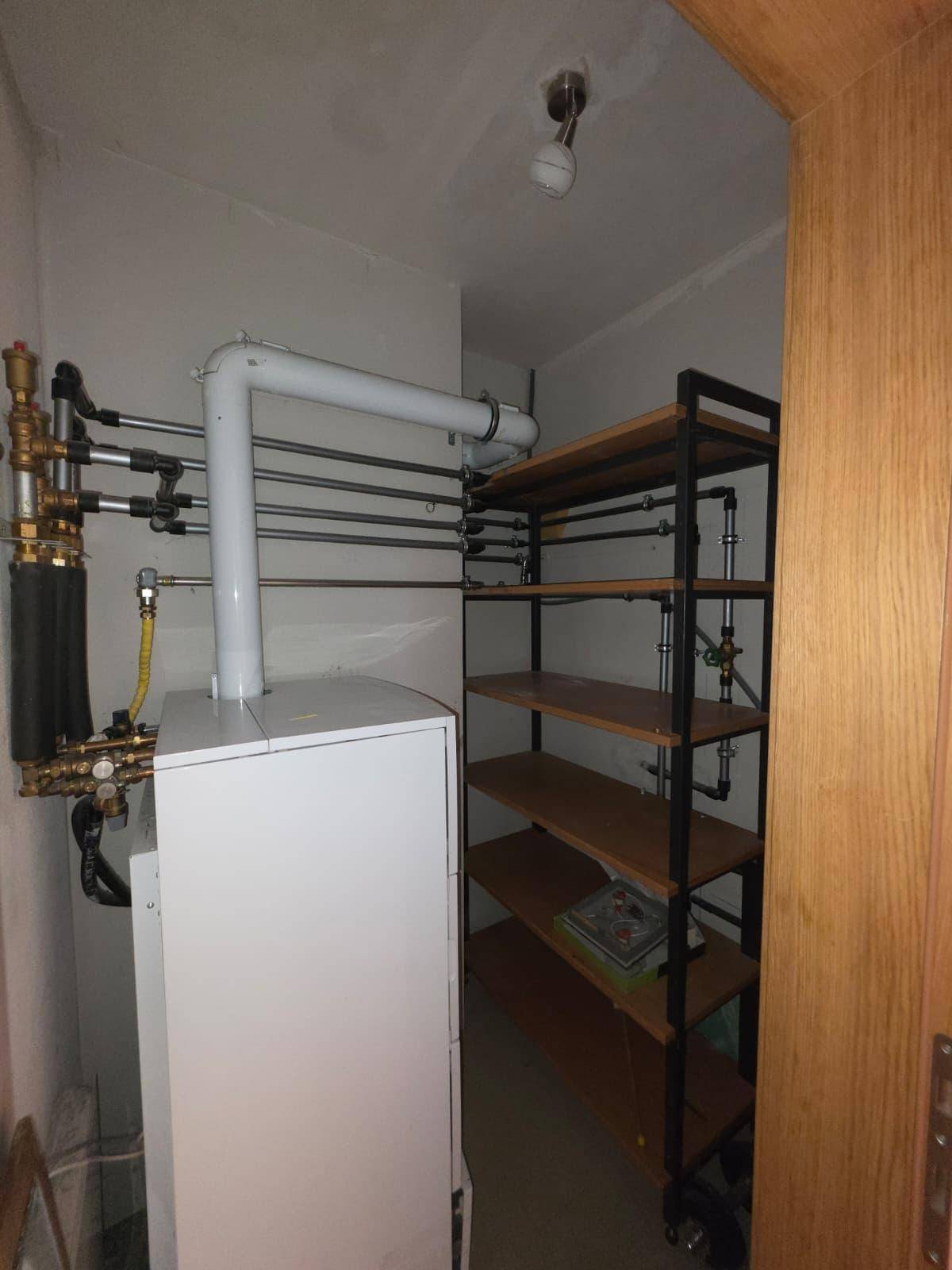 Hauswirtschaftsraum mit Heizungsanlage, Rohrleitungen und praktischem Regal.