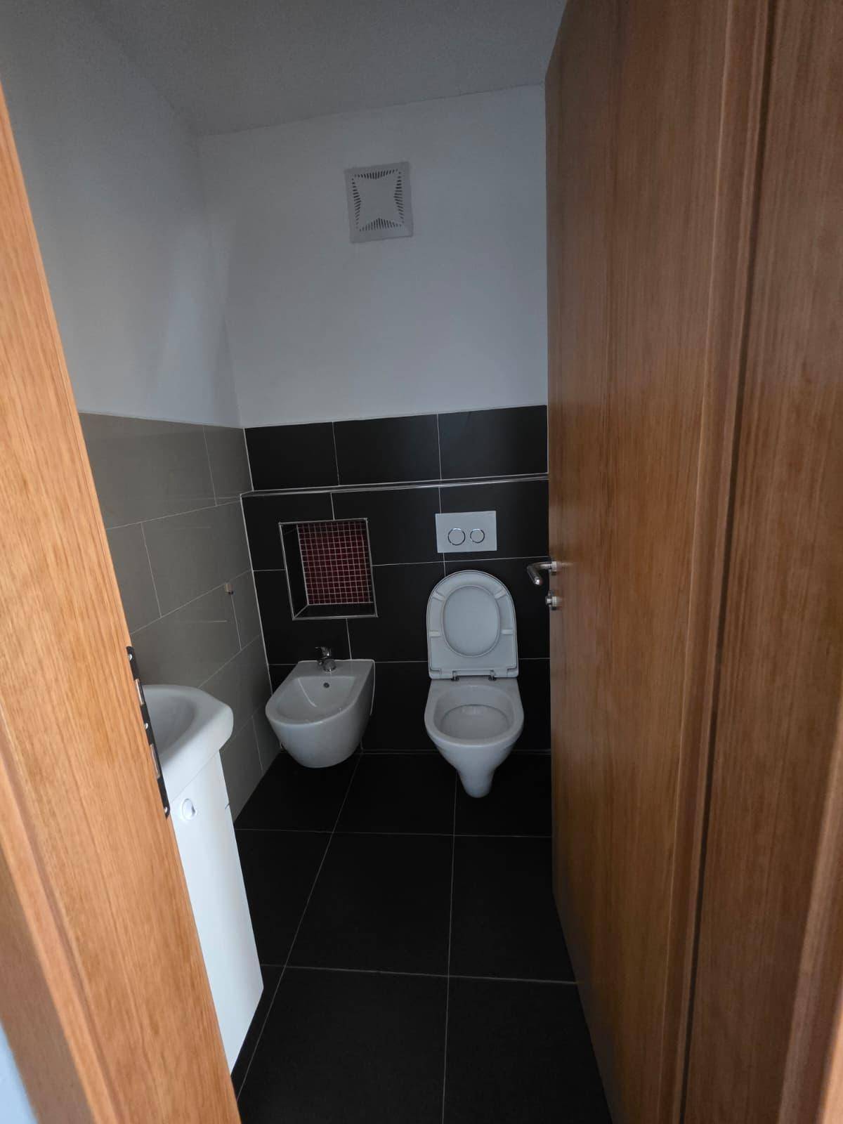 Modernes Gäste-WC mit dunklen Fliesen, Bidet und wandhängendem WC.