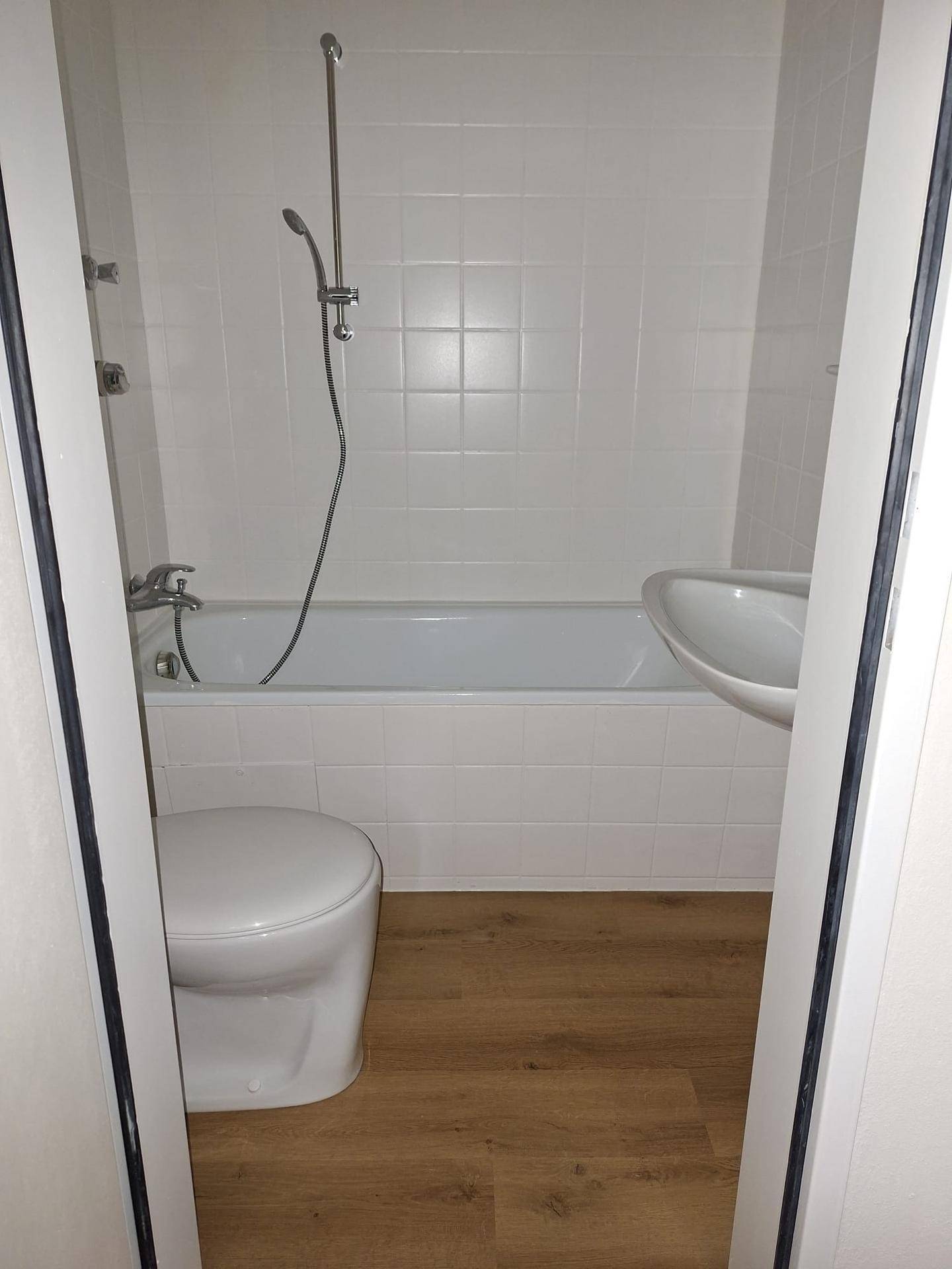 Funktionales Badezimmer mit Badewanne, Toilette und Waschbecken, komplett gefliest.
