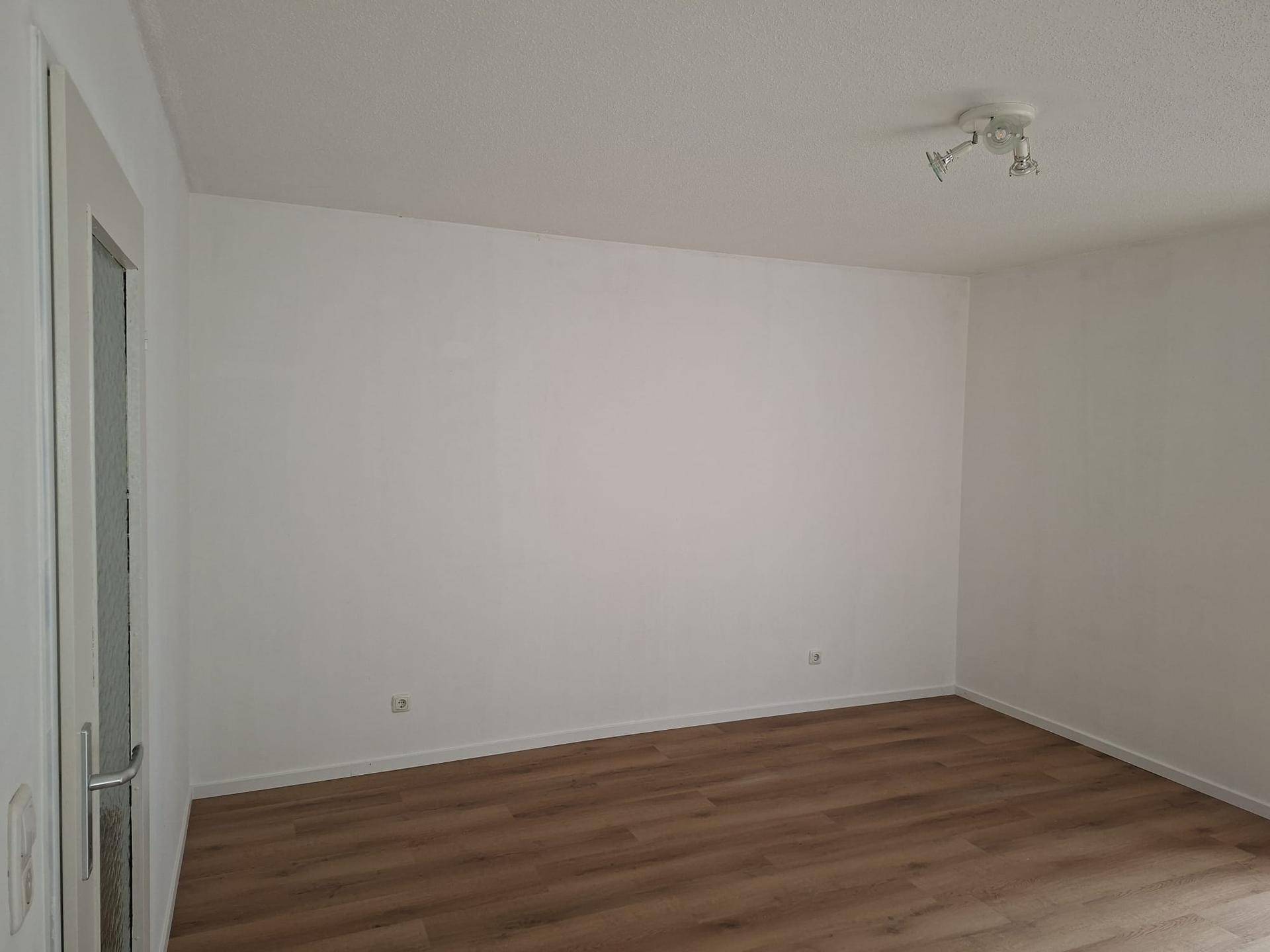 Detailansicht einer weißen Wand und einer modernen Tür mit Glaseinsatz in einem hellen Raum.