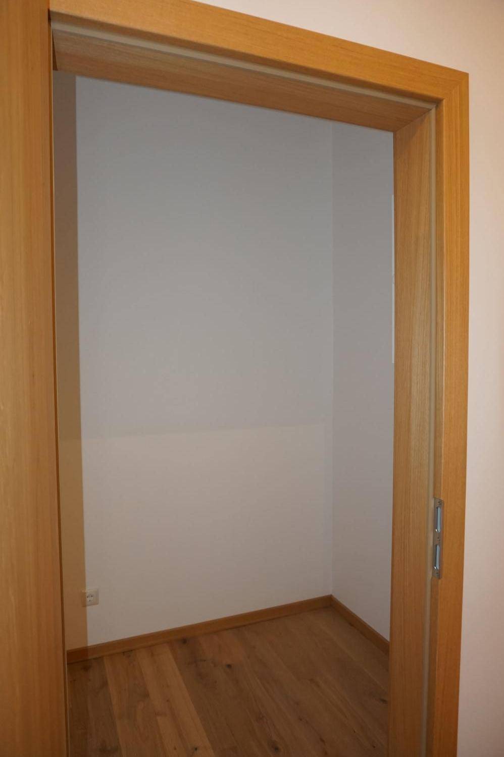 Kleiner Abstellraum mit Holzboden und weißen Wänden, ideal für zusätzlichen Stauraum im Haus.