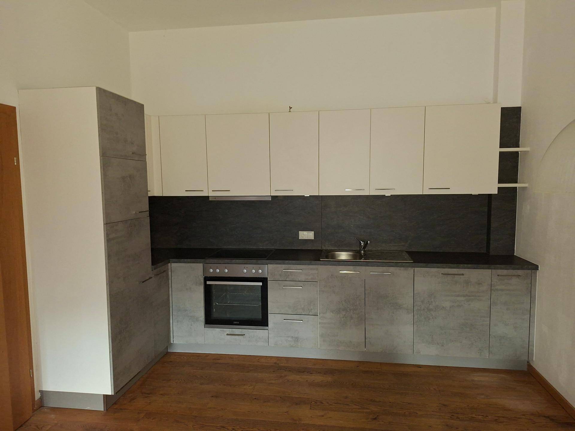 Moderne Einbauküche mit hellen Ober- und grauen Unterschränken sowie dunklem Holzboden.