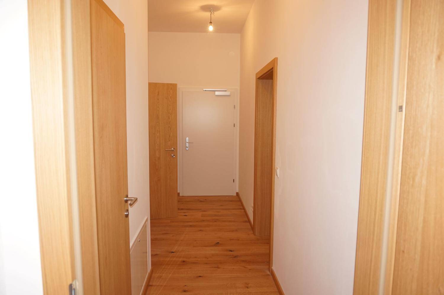 Heller Flur mit Holzboden und mehreren Holztüren, die zu den verschiedenen Zimmern führen.