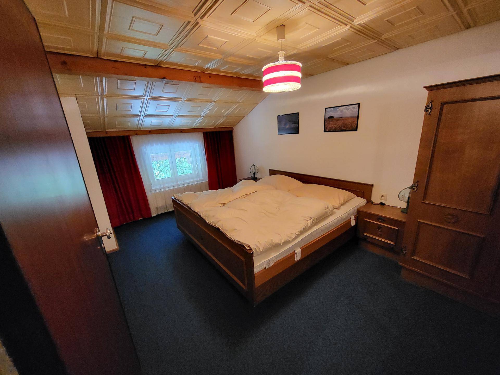 Geräumiges Schlafzimmer mit Doppelbett, blauem Teppichboden und Dachschräge.
