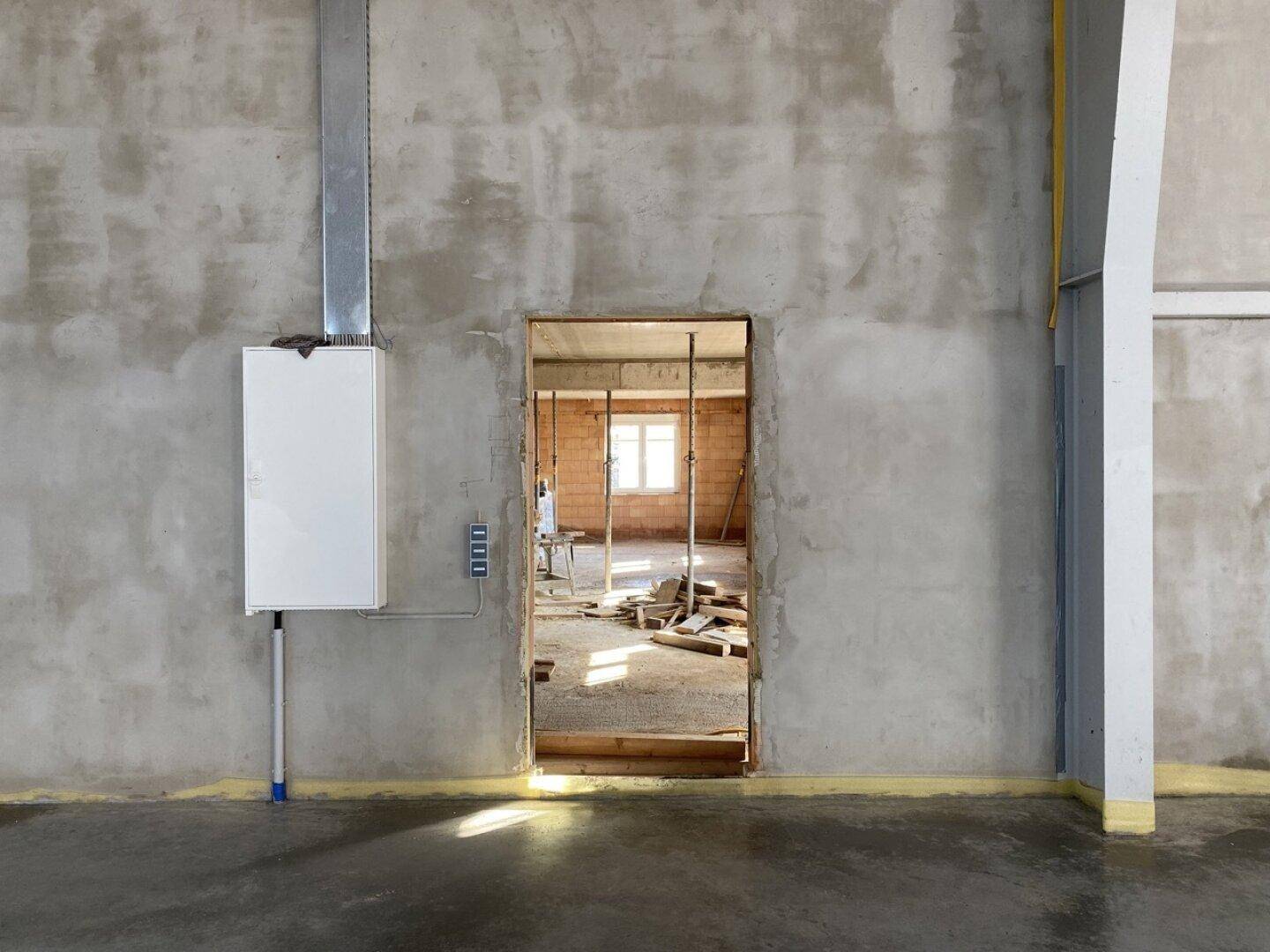 Rohbau eines Raumes mit unverputzten Wänden und einem Fenster, bereit für den Ausbau.