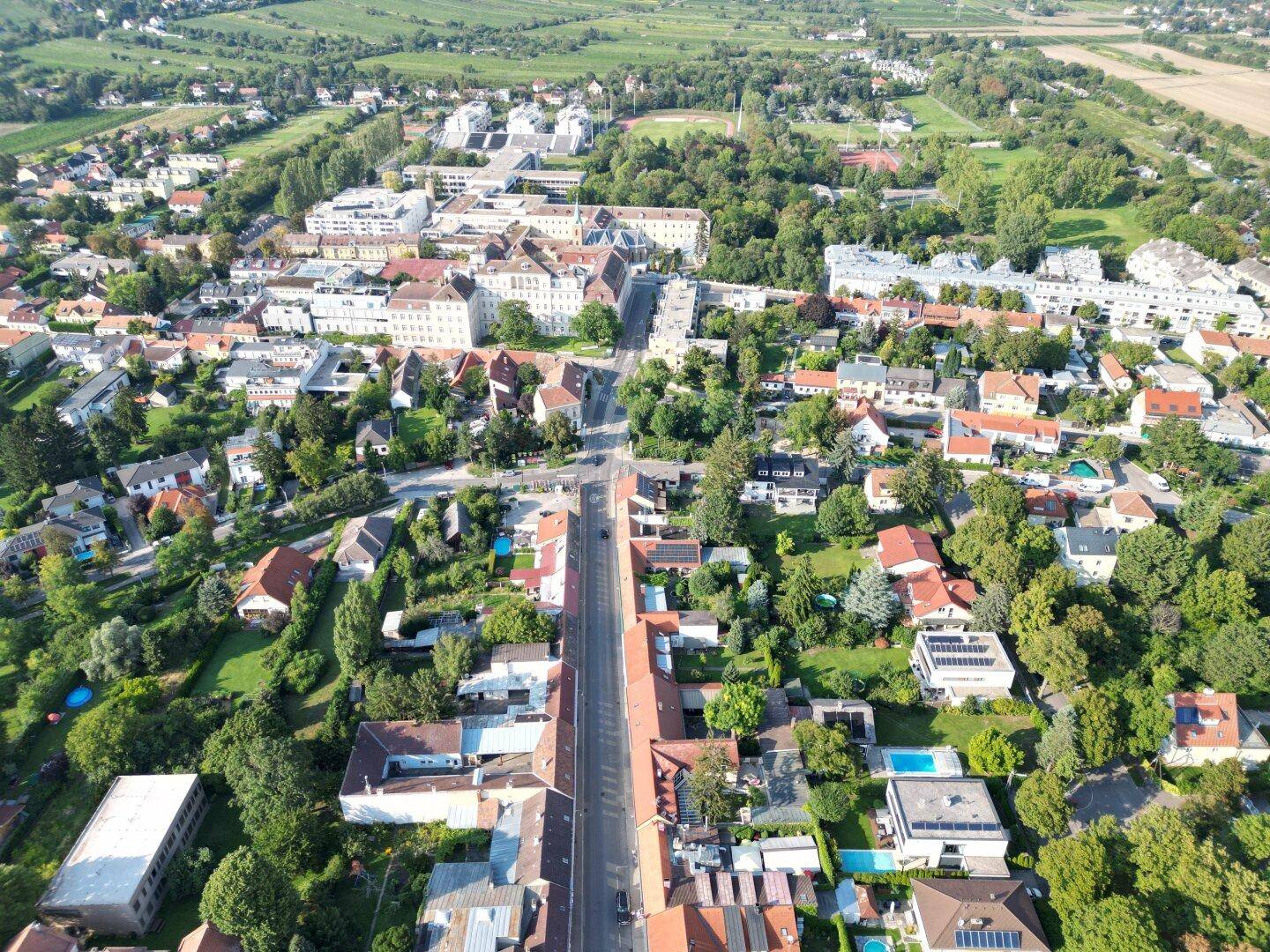 Überblick über eine Wohngegend mit einer Hauptstraße, Häusern und einigen Pools.