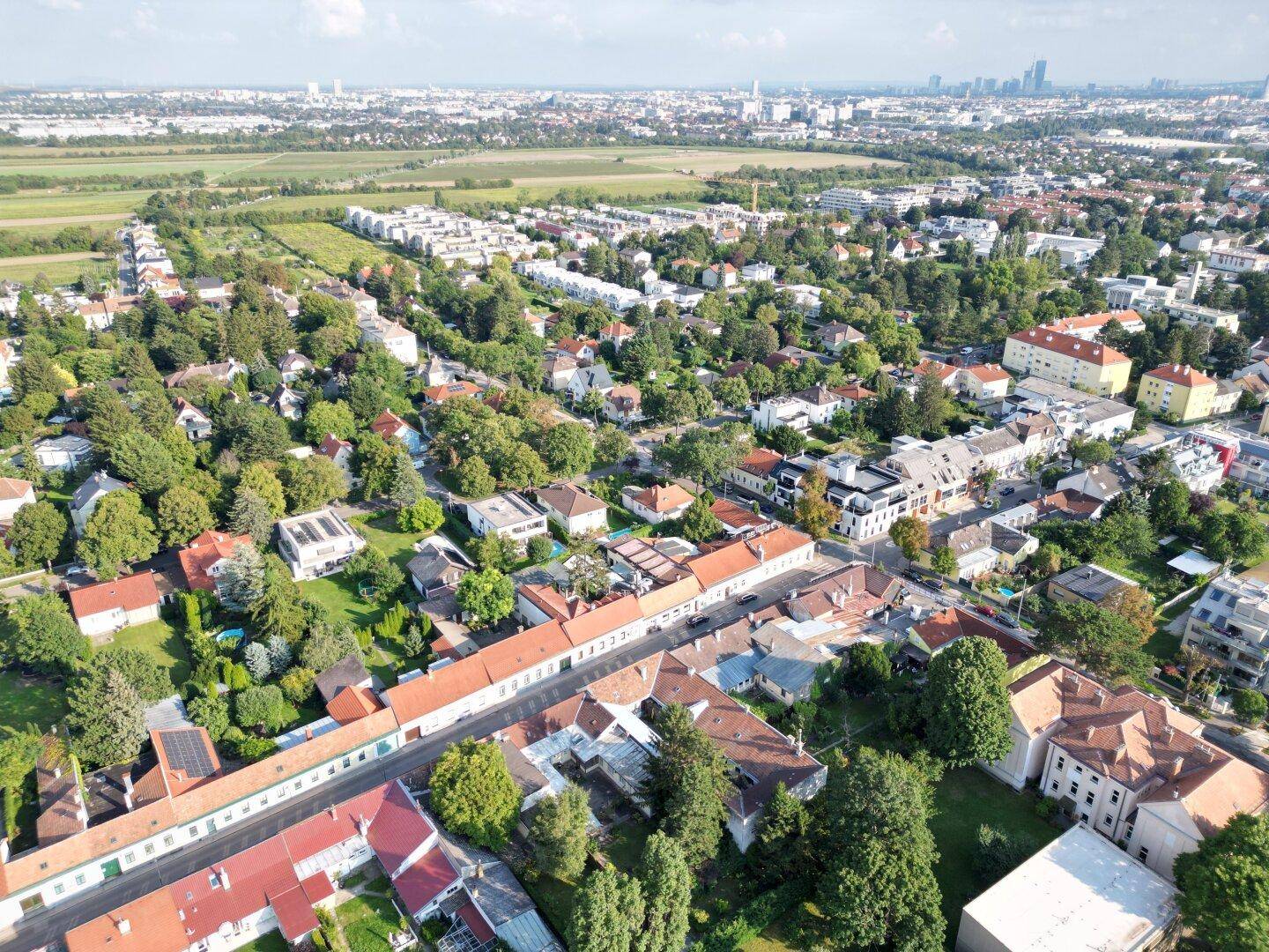 Weitläufige Luftaufnahme einer Stadt mit vielen Grünflächen und Wohngebäuden.