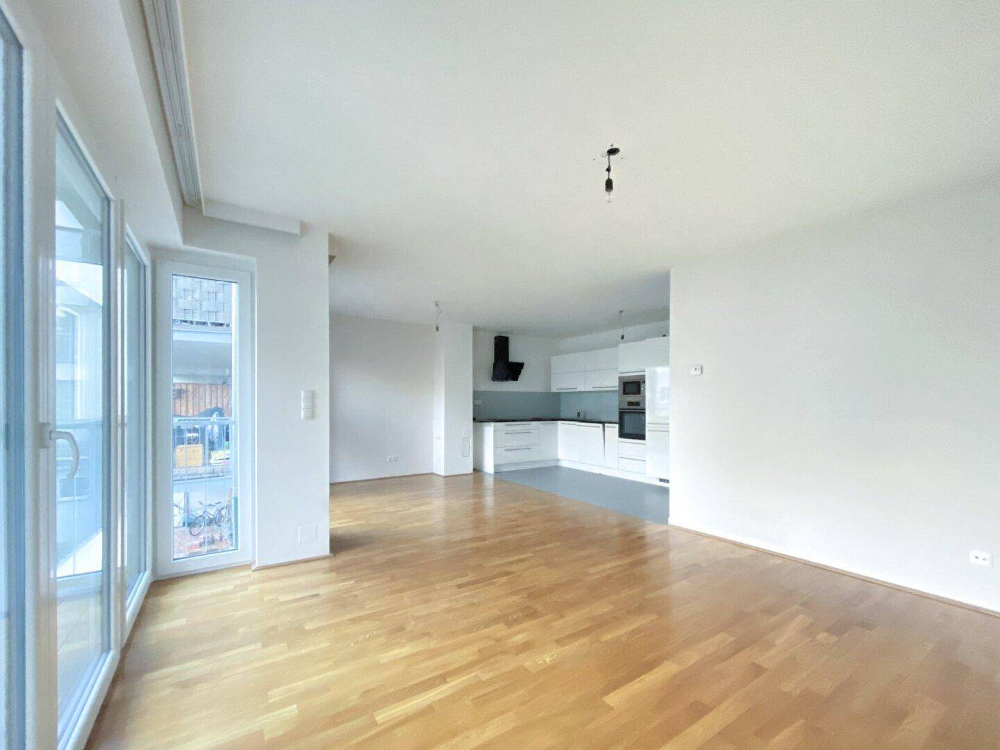 Offener Wohn- und Essbereich mit integrierter, moderner Küche und Zugang zum Balkon.