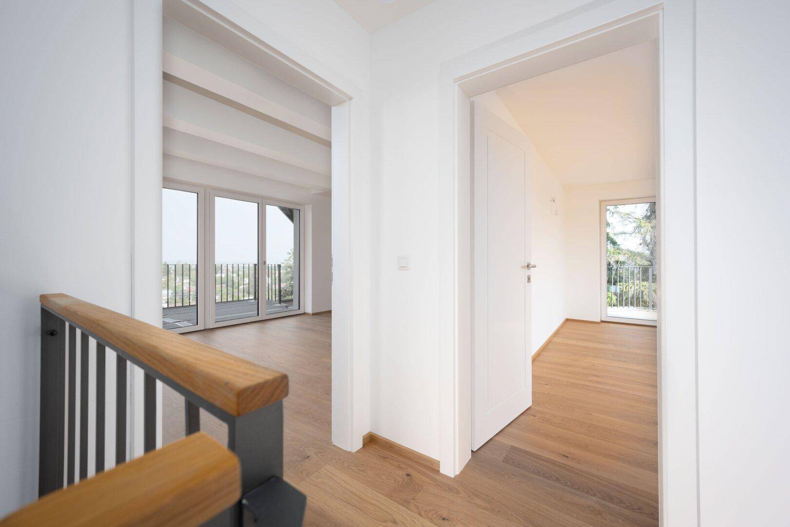 Heller Flur mit Holzboden und Blick in angrenzende Räume mit Balkonzugang.