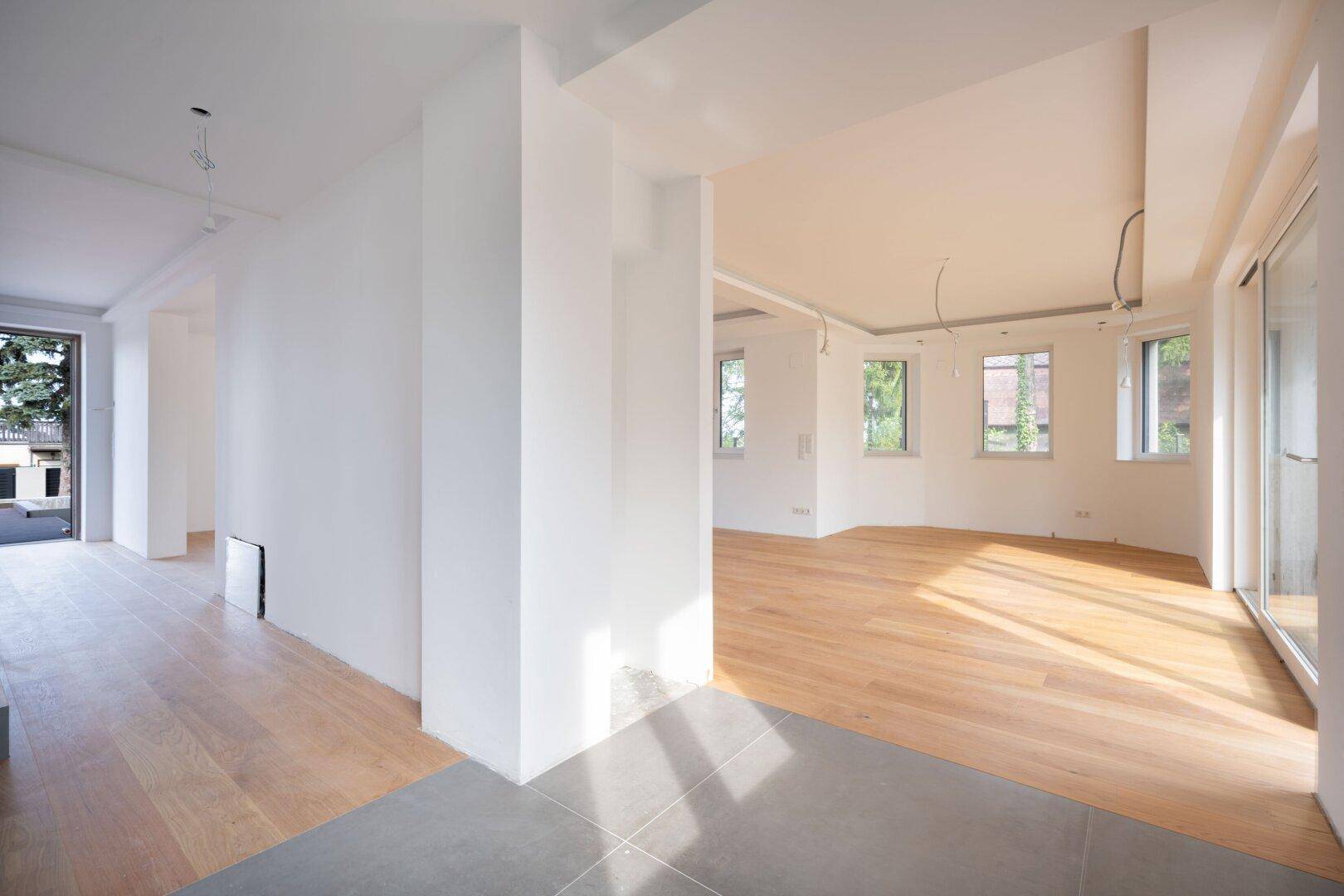 Offener Übergangsbereich mit Holzboden und Fliesen, der zu einem hellen Wohnraum führt.