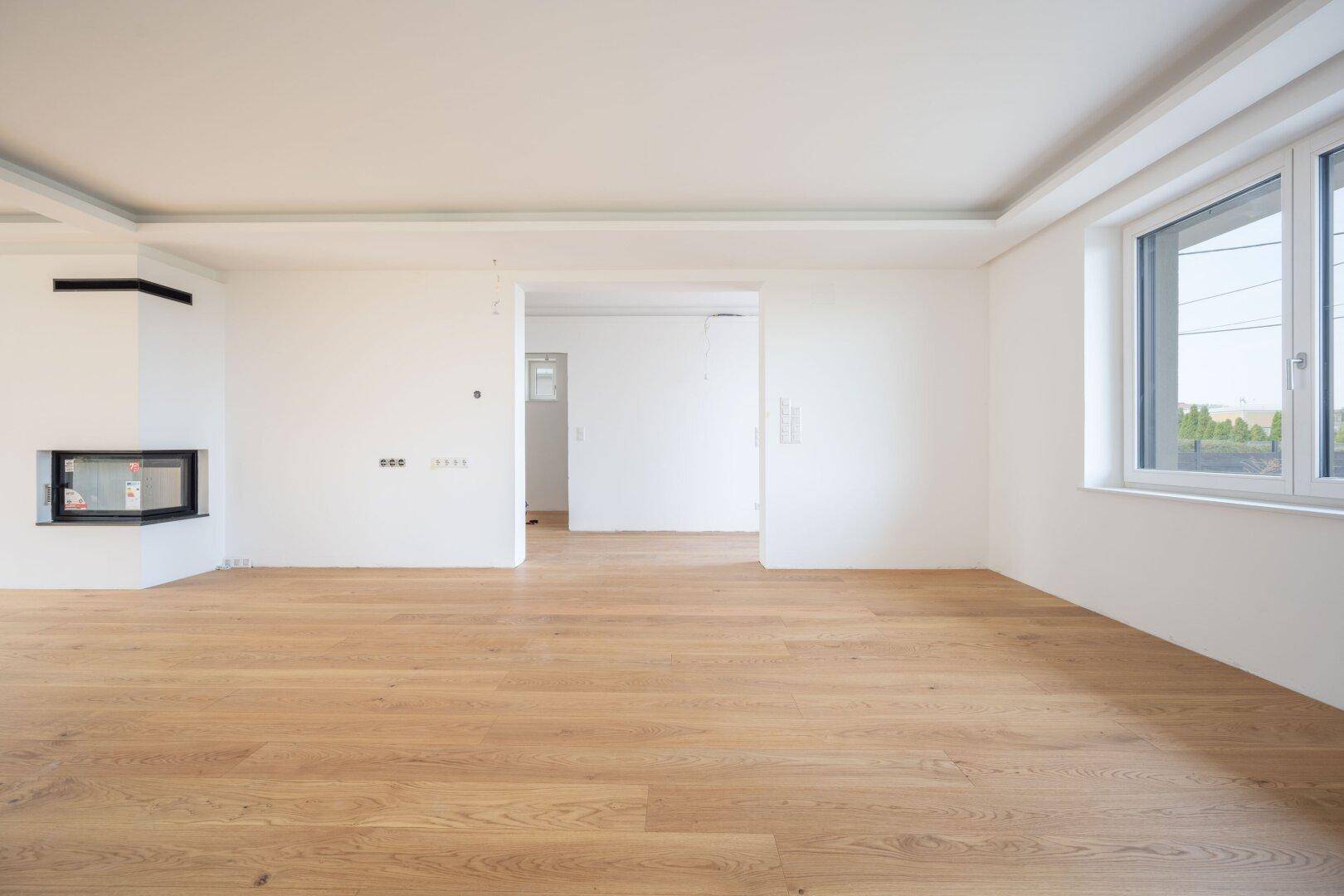 Heller Wohnbereich mit Holzboden und modernem Kamin, bereit für individuelle Gestaltung.