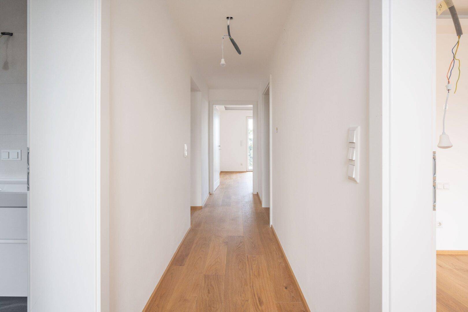 Langer, heller Flur mit Holzboden, der zu weiteren Räumen im Haus führt.