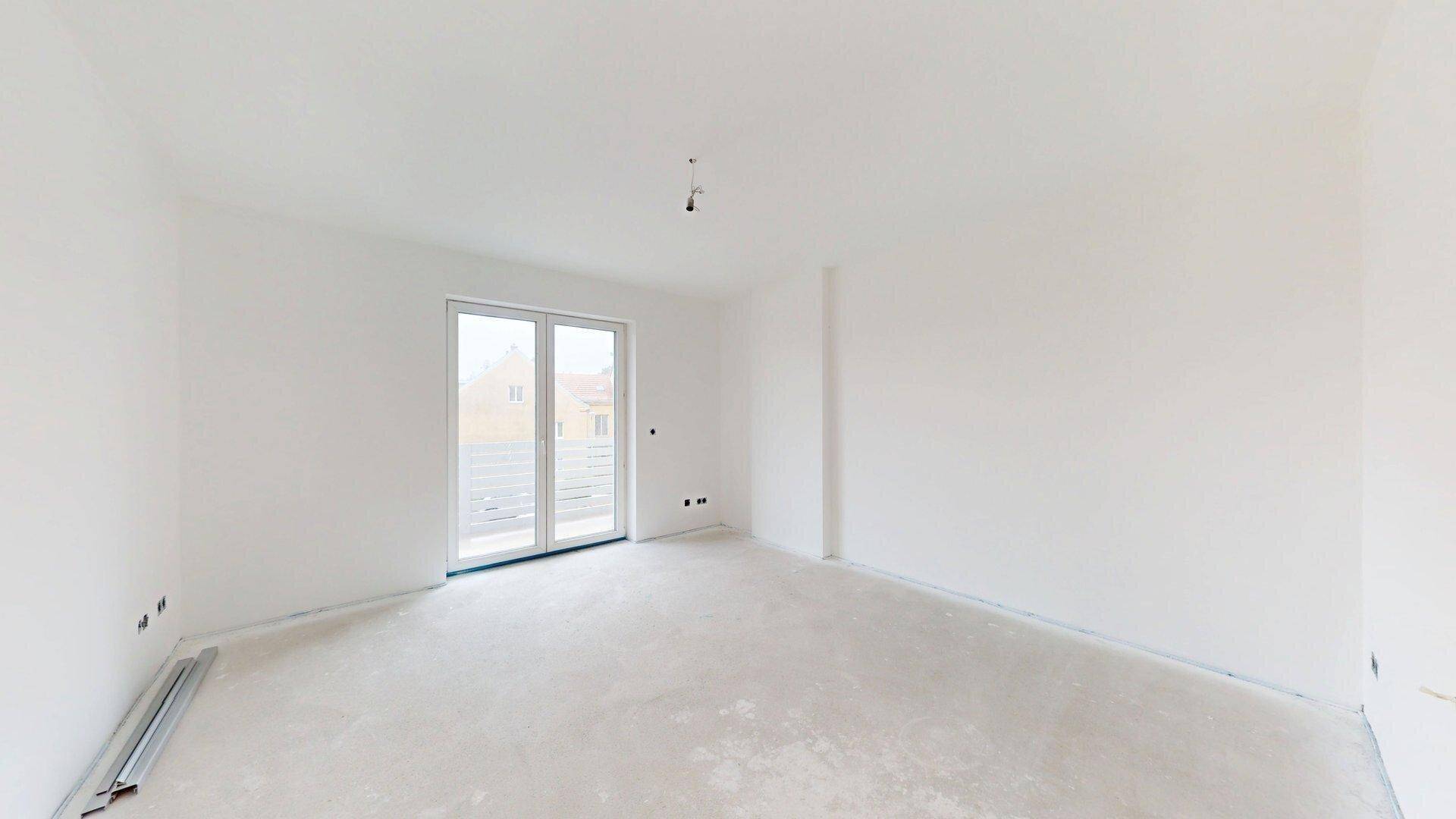 Schlafzimmer im Rohbau mit großer Tür zum Außenbereich, ideal für direkten Zugang zum Garten oder Balkon.
