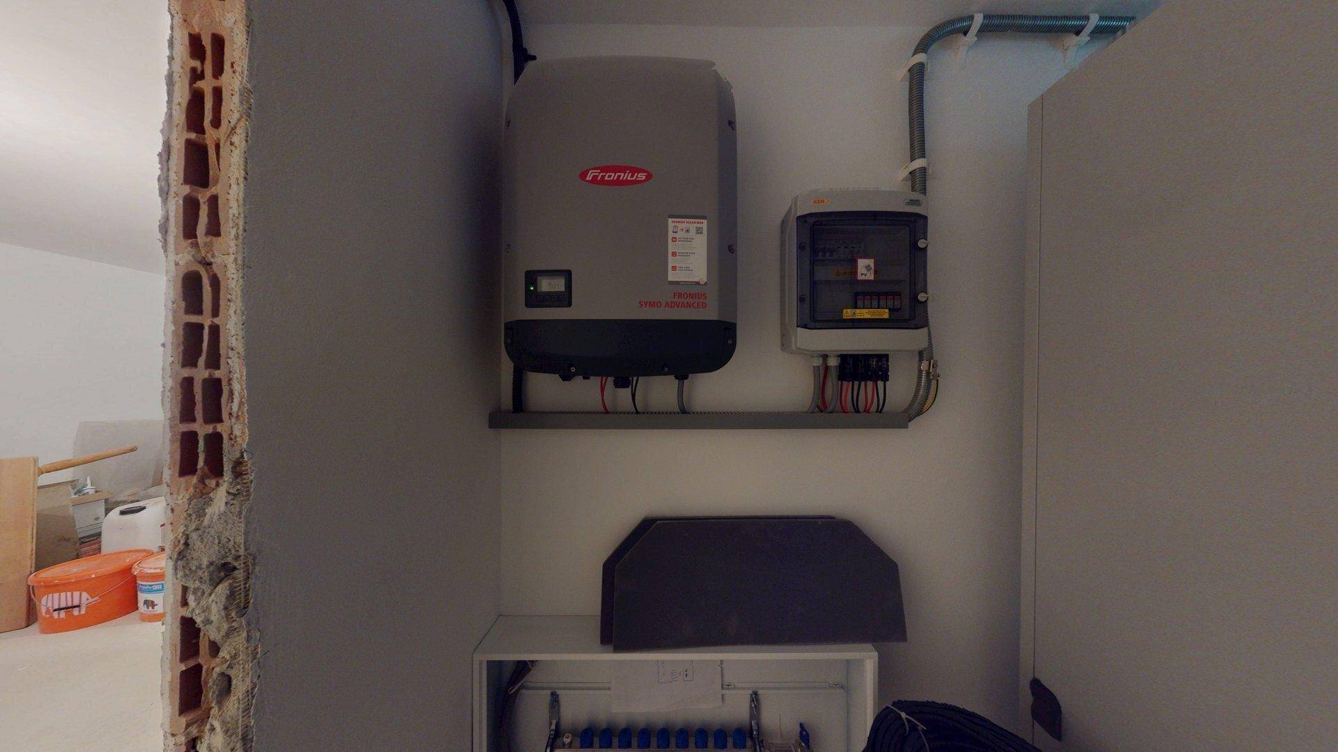 Solarwechselrichter und Schaltkasten in einem Technikraum mit unverputzter Wand, der sich im Bau befindet.