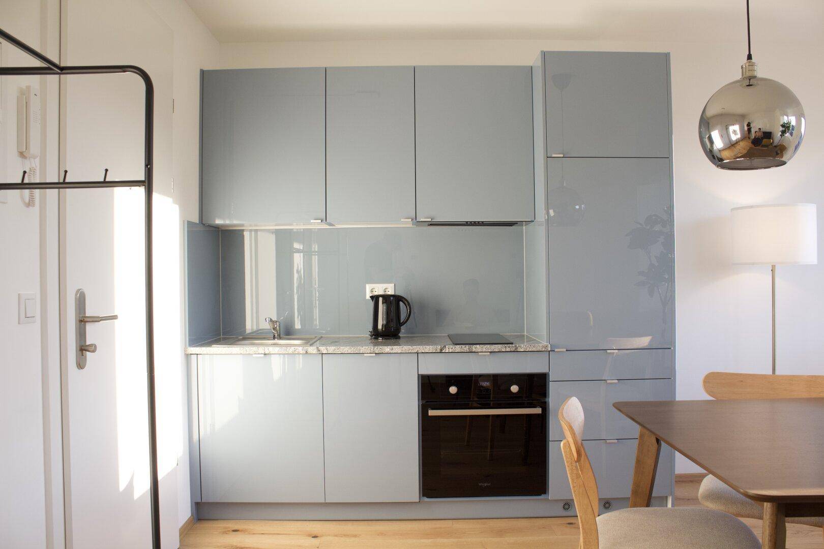 Moderne Küchenzeile in Hellblau mit integriertem Backofen und Induktionskochfeld.