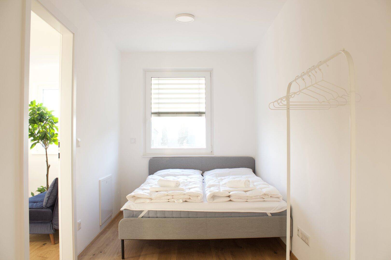 Gemütliches Schlafzimmer mit Doppelbett, Holzboden und viel natürlichem Licht.