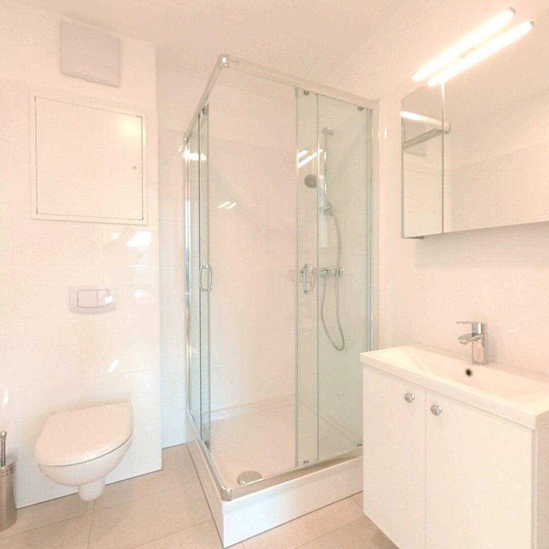 Modernes Badezimmer mit Duschkabine, wandhängendem WC und Spiegelschrank.