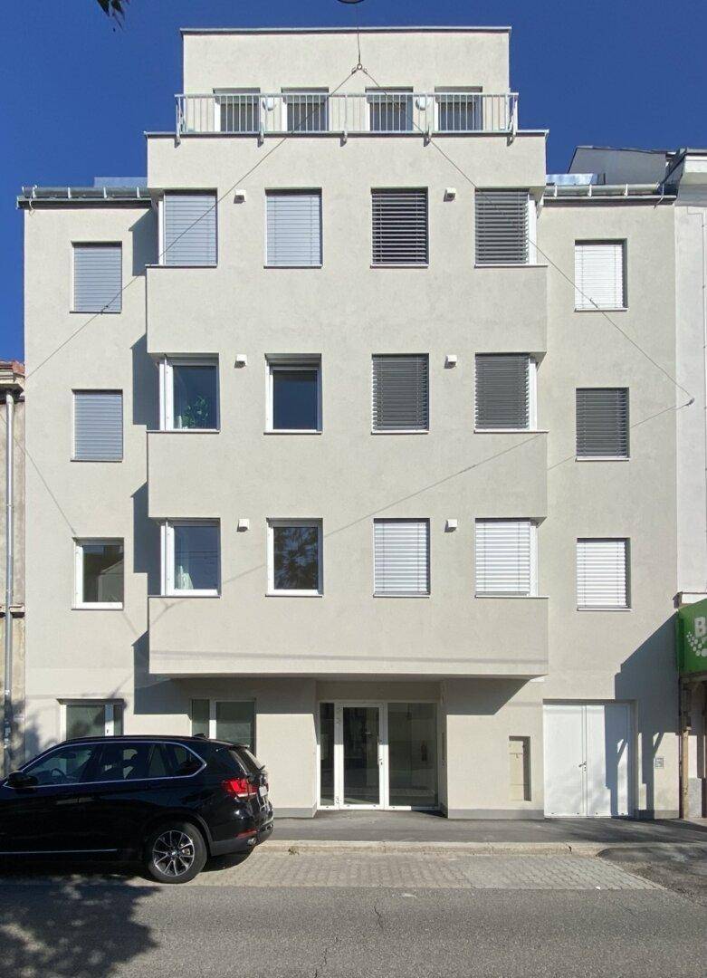 Moderne Wohnhausfassade mit vielen Fenstern und Balkonen in städtischer Umgebung.