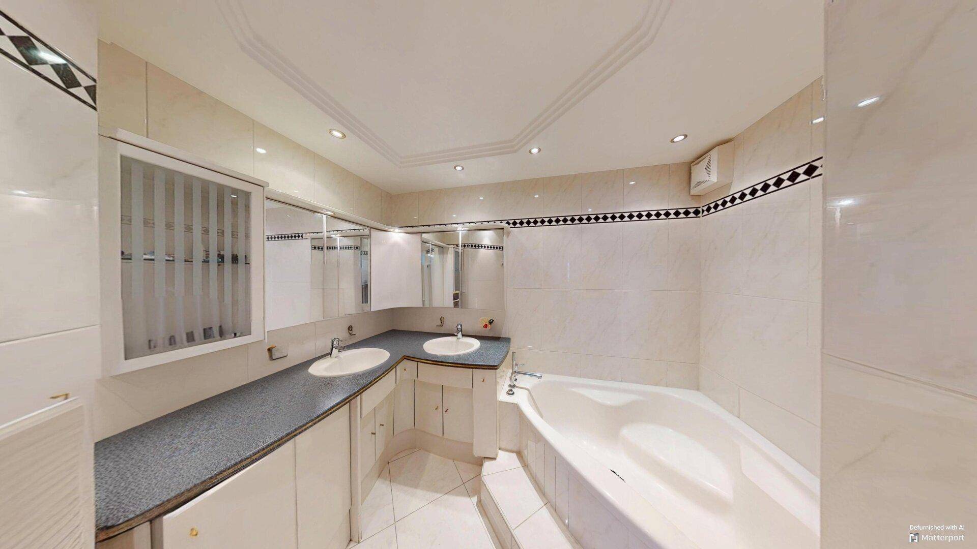 Geräumiges Badezimmer mit Doppelwaschbecken, eingebauter Badewanne und dekorativen Fliesen.