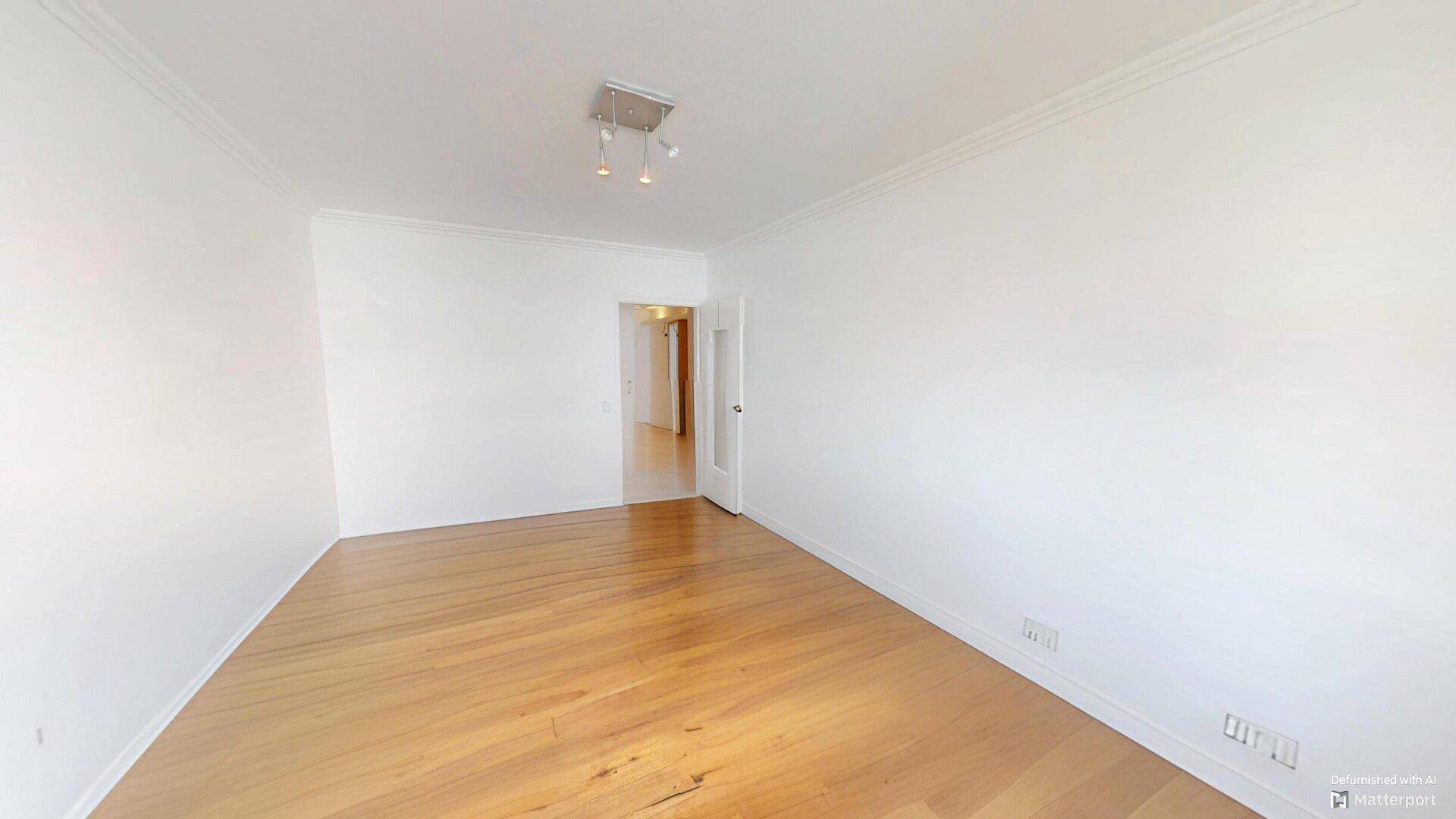 Heller, leerer Raum mit Parkettboden und weißen Wänden, der Zugang zu einem weiteren Zimmer bietet.
