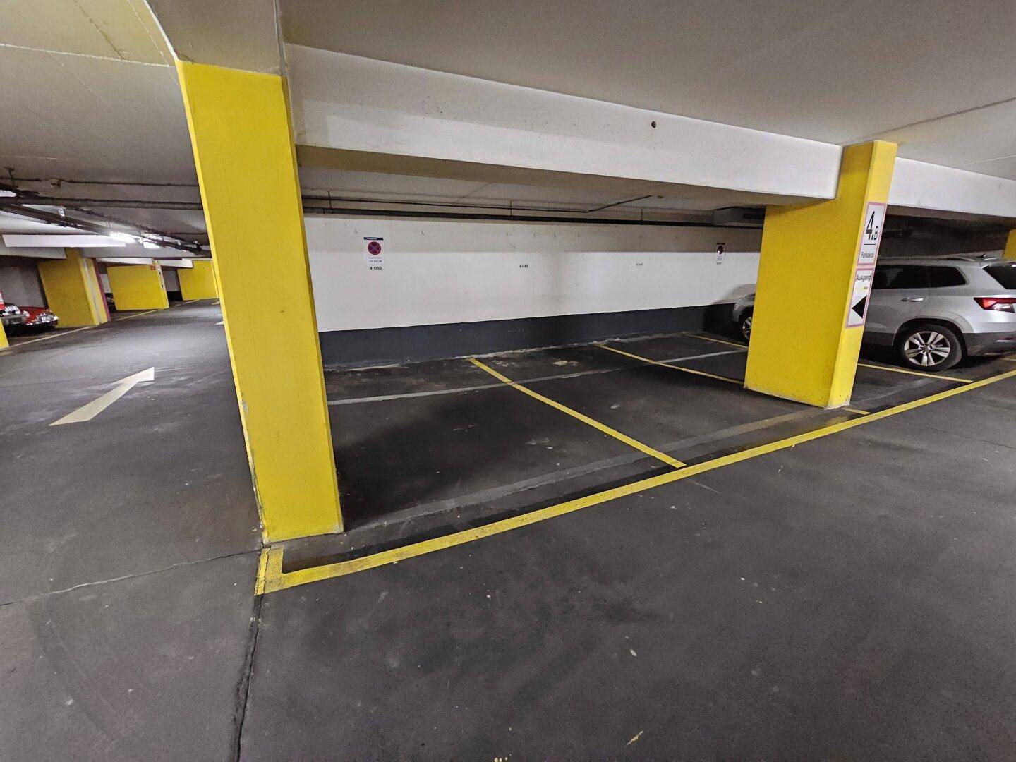 Tiefgarage mit gelben Säulen und markierten Parkplätzen für Fahrzeuge.