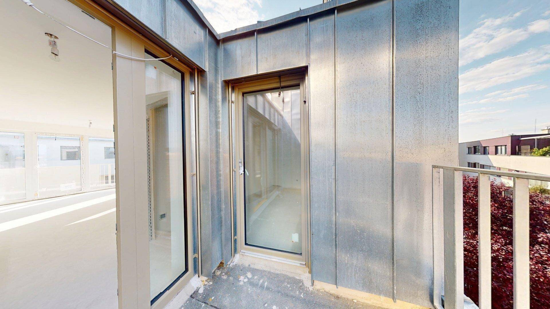 Fassade eines Gebäudes mit Metallverkleidung und Fenster, gesehen von einem angrenzenden Balkon.