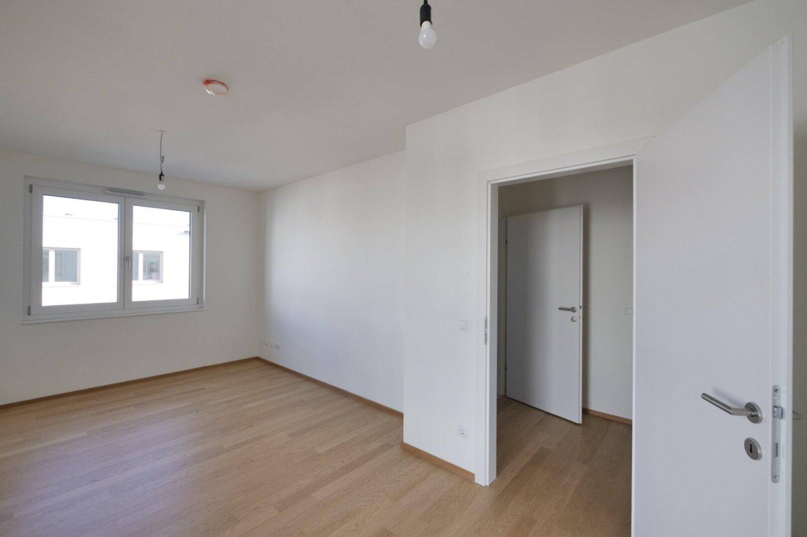 Geräumiges Zimmer mit Parkettboden und Fenster, bereit zur individuellen Gestaltung.