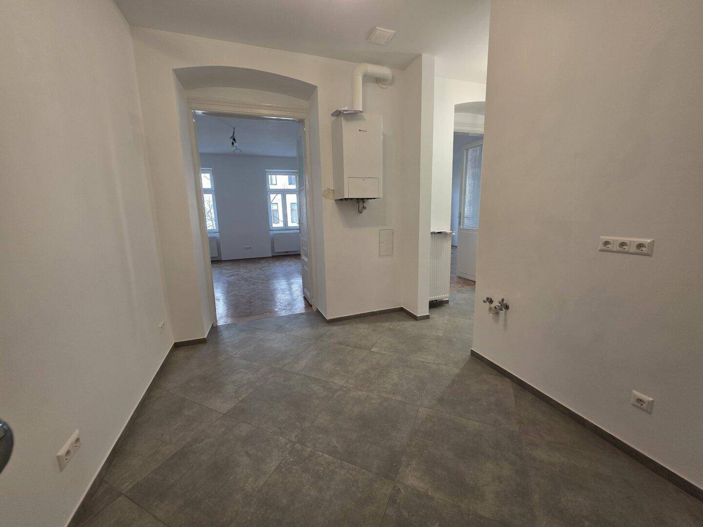 Geräumiger Eingangsbereich mit grauen Fliesen und Zugang zu verschiedenen Zimmern.