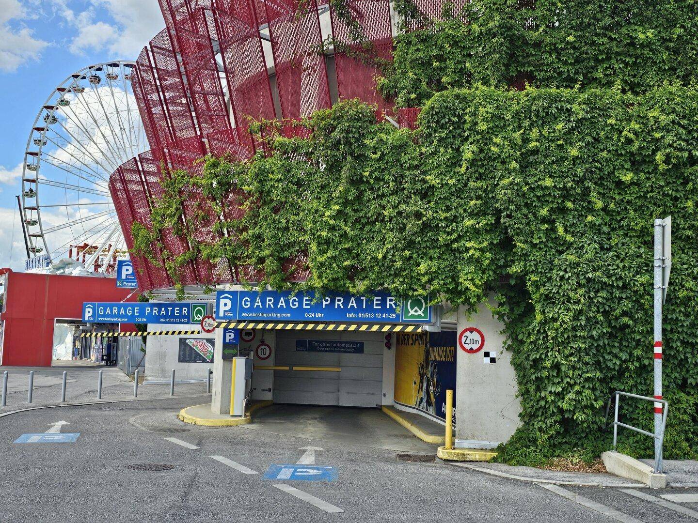 Eingang zu einer Tiefgarage mit einem Riesenrad im Hintergrund.