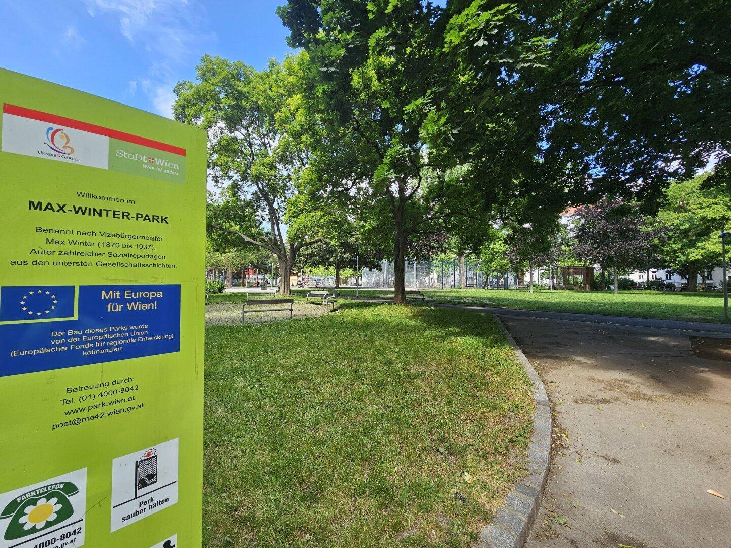 Grüner Stadtpark mit Bäumen und Rasenflächen, ideal zur Erholung.