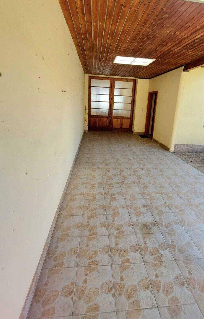 Überdachter Außenbereich mit Fliesenboden und Holzdecke, ideal für entspannte Stunden.