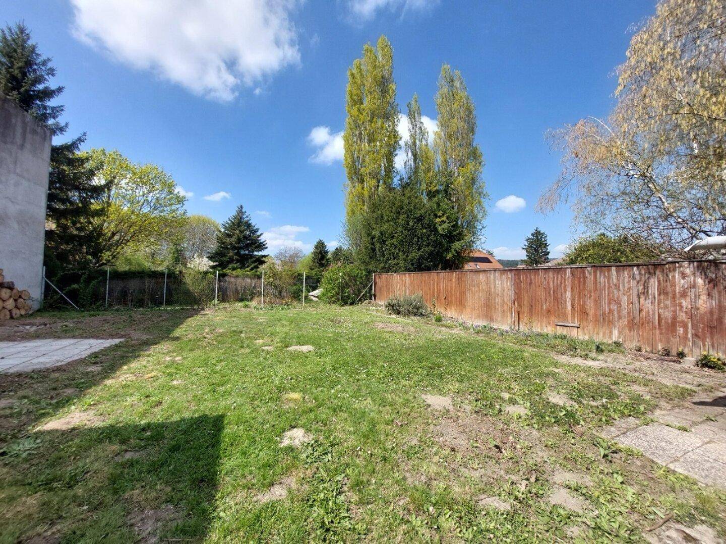 Großer Gartenbereich mit Rasenfläche und Holzzaun, bietet viel Platz im Freien.