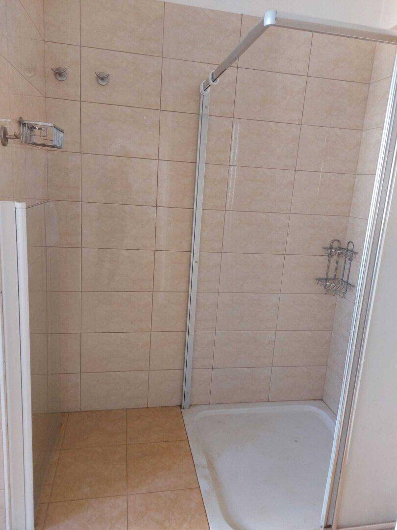 Badezimmer mit beigefarbenen Fliesen und einer Duschkabine, funktional und hell.