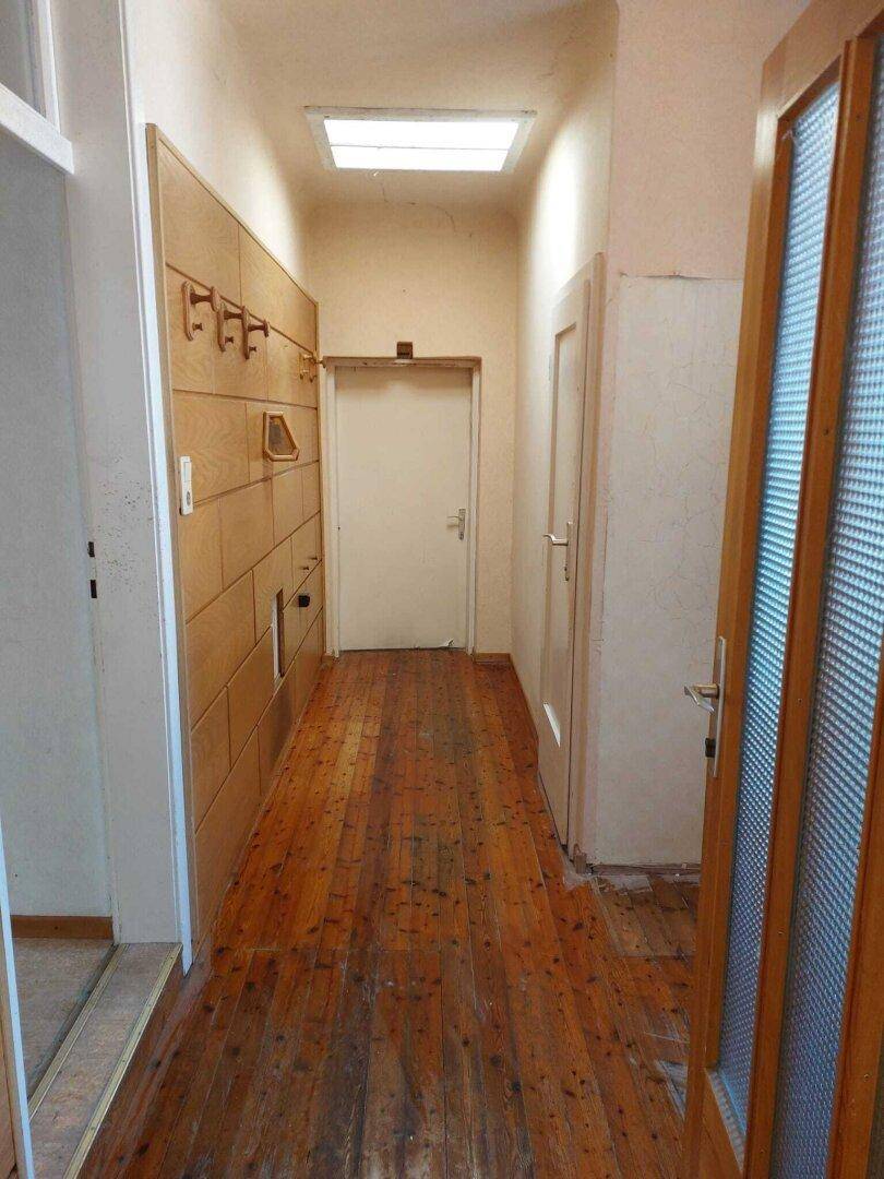 Flur mit Holzdielenboden und einer Holzverkleidung an der Wand, einladend und hell.