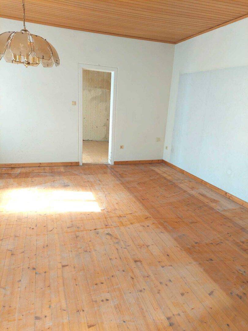 Leeres Zimmer mit Holzdielenboden und Holzdecke, ideal für eine individuelle Gestaltung.