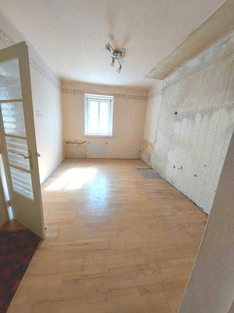 Kleines Zimmer mit Laminatboden und einem Fenster, das Renovierungsbedarf zeigt.
