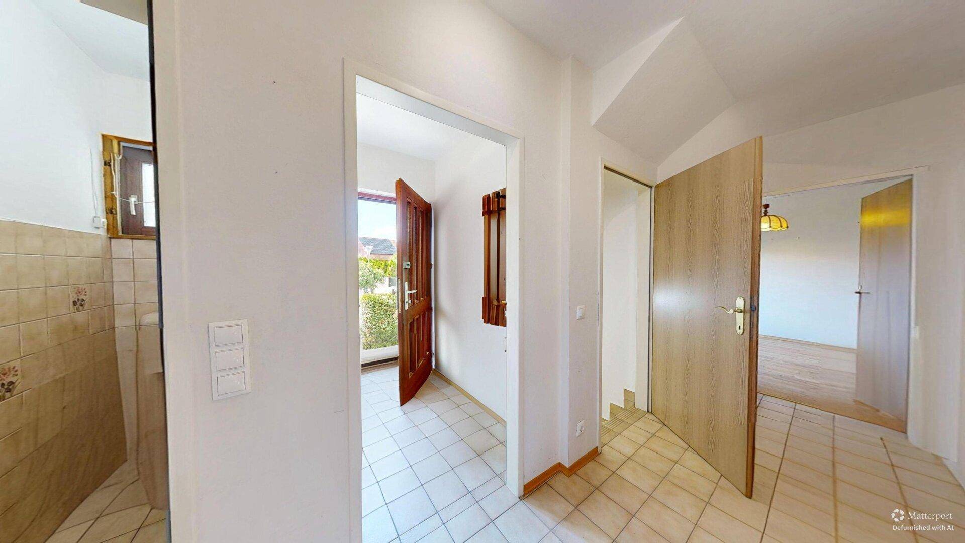 Heller Eingangsbereich mit Fliesenboden und Zugang zu verschiedenen Räumen des Hauses.