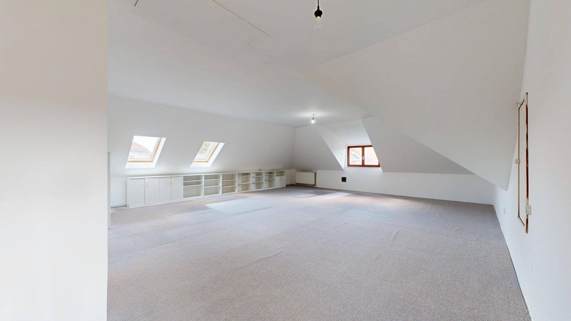 Helles Dachzimmer mit Teppichboden, Dachfenstern und vielseitig nutzbarer Fläche.