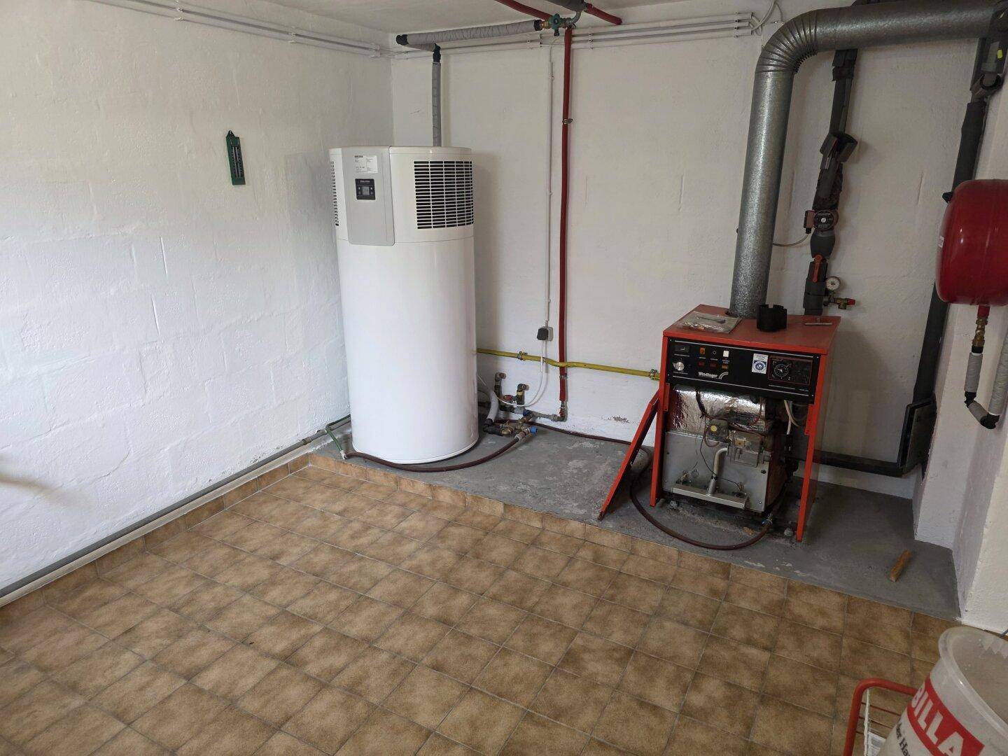 Heizungsraum im Keller mit Wärmepumpe und älterer Heizungsanlage.