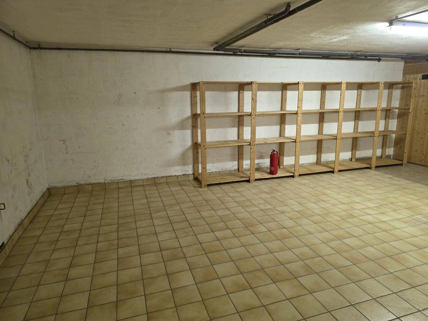 Geräumiger Lagerraum im Keller mit Holzregalen und Fliesenboden für zusätzlichen Stauraum.
