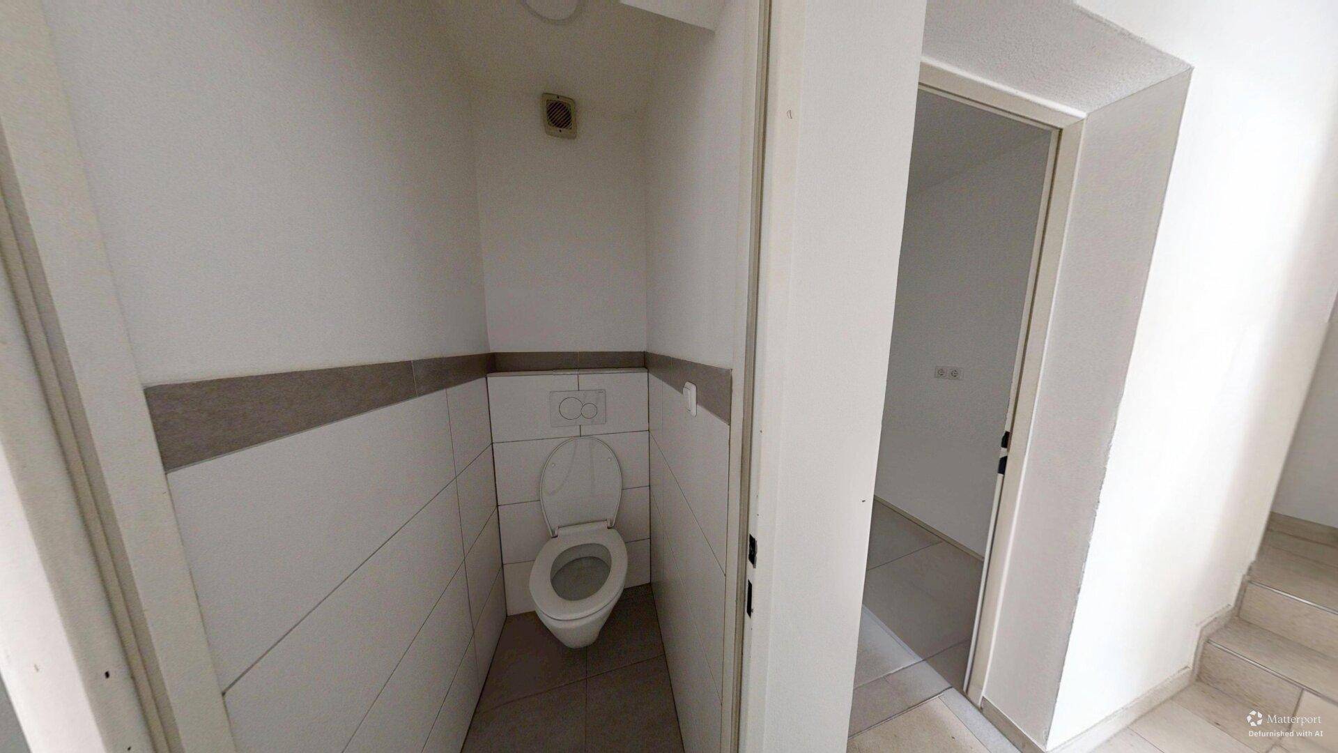 Kleines Gäste-WC mit Wand-WC und halbhohen Fliesen in neutralen Farben.