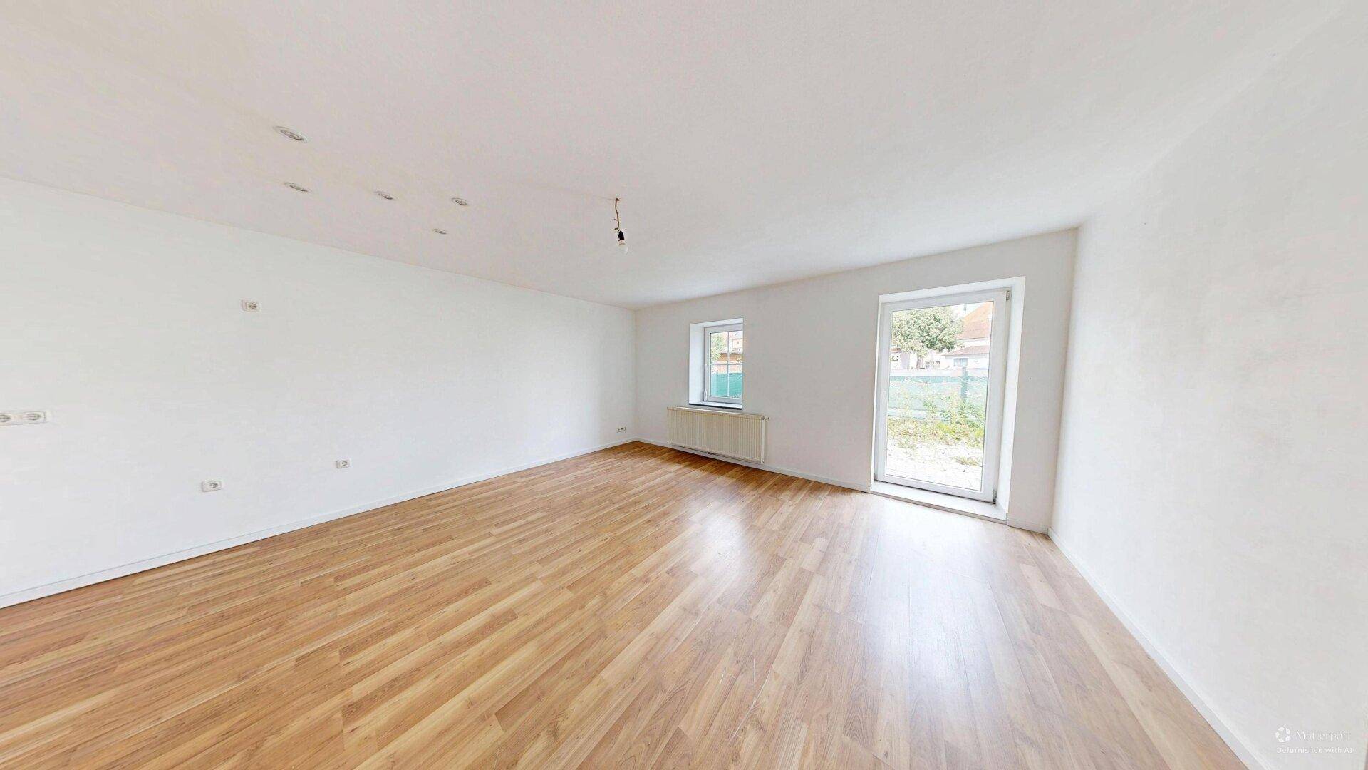 Geräumiges, helles Zimmer mit Laminatboden und Zugang zum Außenbereich.