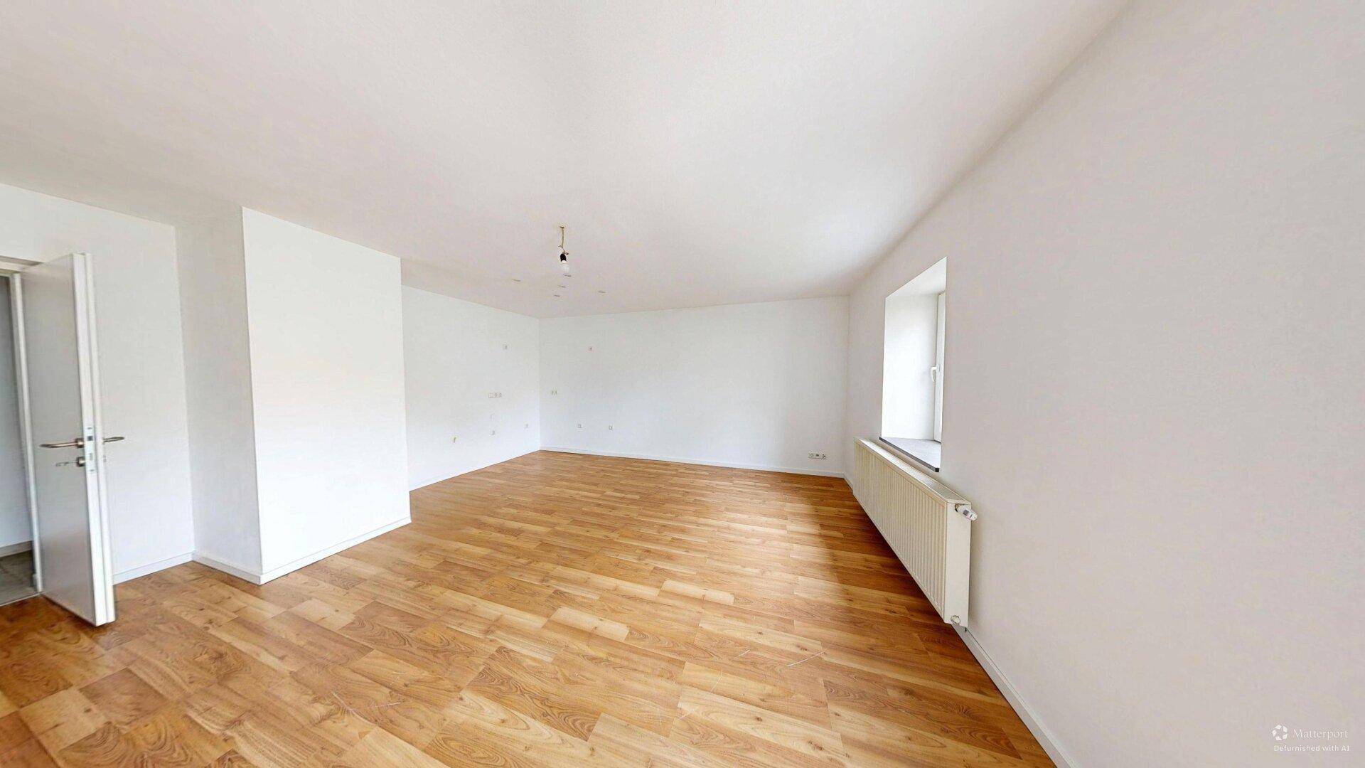Großes, helles Zimmer mit Laminatboden und weiß gestrichenen Wänden.