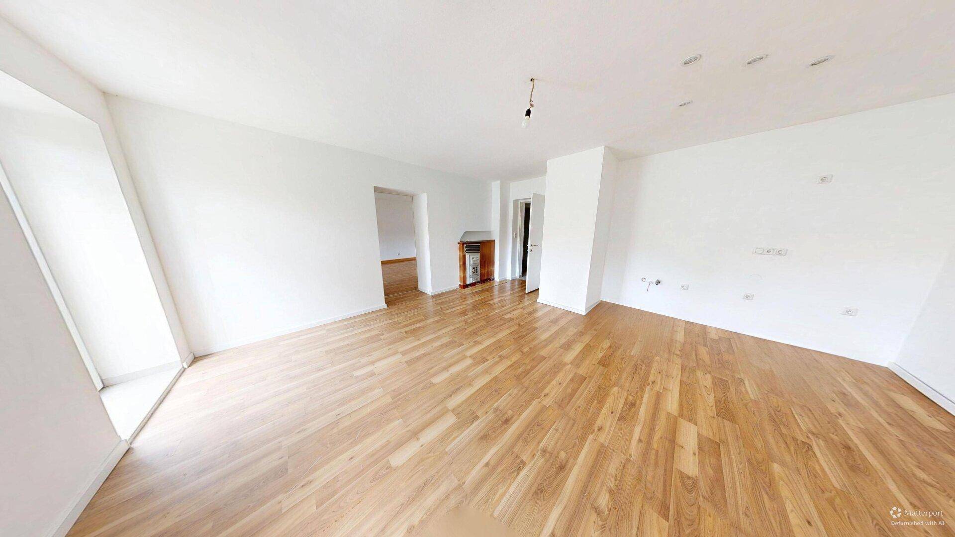 Helles Wohnzimmer mit Laminatboden und einem Heizkörper, bereit zur individuellen Gestaltung.
