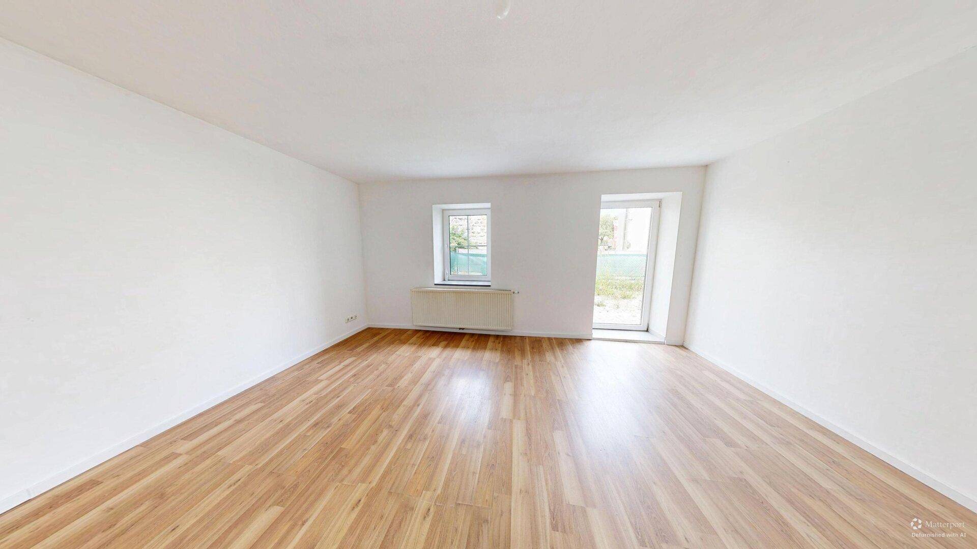 Helles Zimmer mit Laminatboden und Zugang zu einem Außenbereich, ideal für Familien.