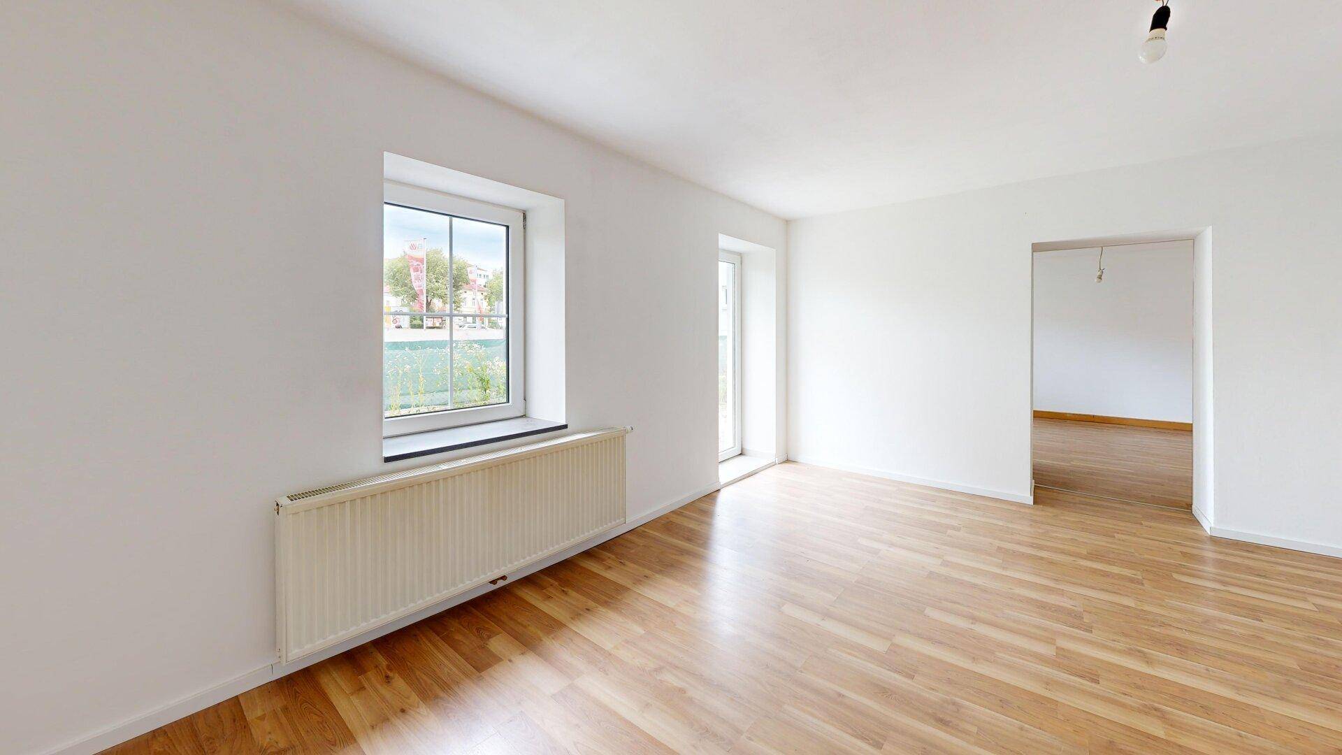 Helles Zimmer mit Laminatboden, Fenster und Tür zum Außenbereich, vielseitig nutzbar.