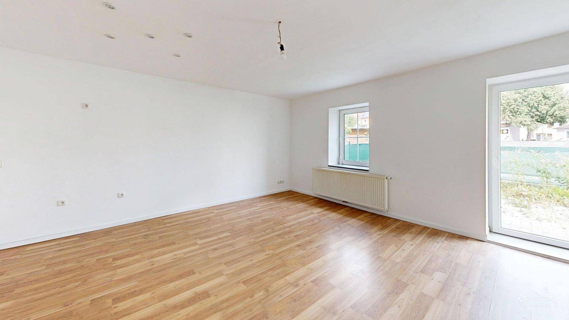 Helles Zimmer mit Laminatboden, Fenster und Tür zum Außenbereich, vielseitig nutzbar.
