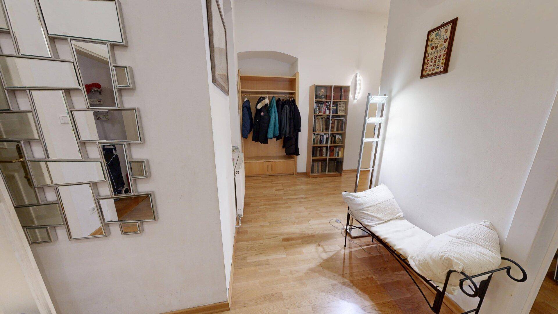 Heller Flur mit Parkettboden, Garderobe und dekorativem Spiegel, der zum Wohnbereich führt.